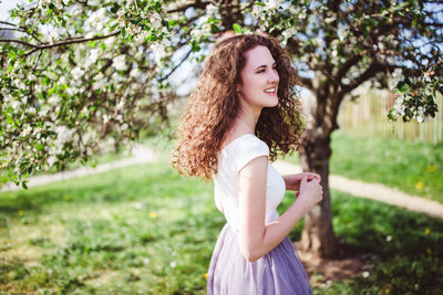 Beautiful young woman standing against tree