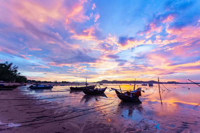 Boats moored in sea against sky during sunset