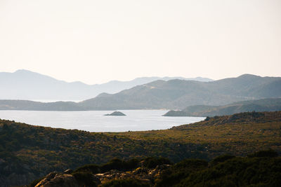 Scenic view of sea and mountains against clear sky