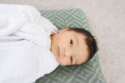 High angle portrait of cute baby girl lying on bed