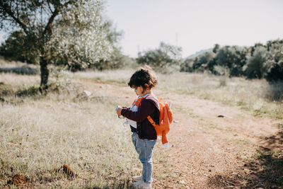 Side view of child taking pictures on field