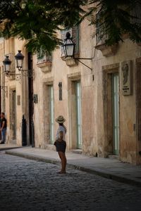 Rear view of woman walking on street amidst buildings