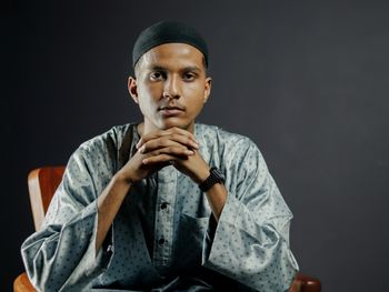 Portrait of senior man drinking water against black background