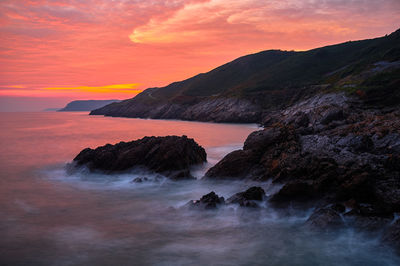 Scenic view of sea against dramatic sky during sunset