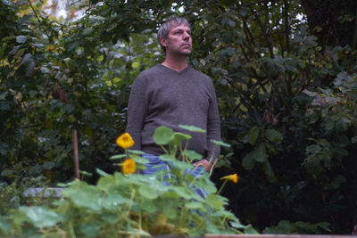 Young man standing against plants