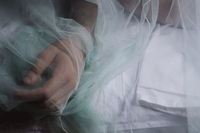 High angle view of person lying on bed seen through netting