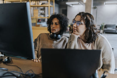 Dedicated female programmers using computer while working at desk in creative workplace