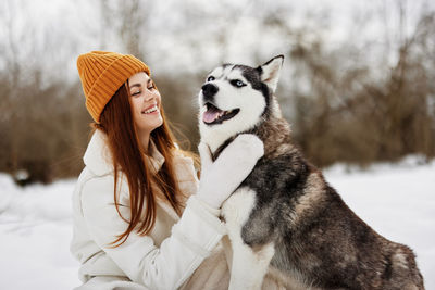 Portrait of woman with dog on snow covered field