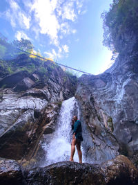 Rear view of woman on rock against sky