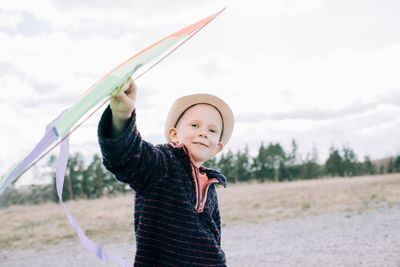 Portrait of boy standing on field against sky