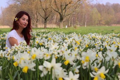 Beautiful woman standing by flowering plants on field