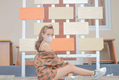 Portrait of smiling young woman standing against wall