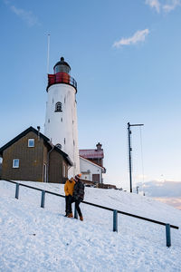 Man standing on snow covered building against sky