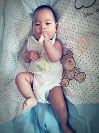 Portrait of cute baby girl sitting on bed