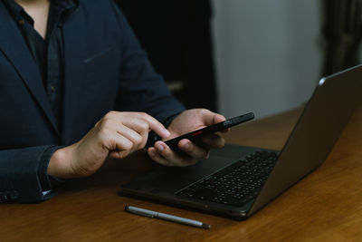 Midsection of man using laptop on table