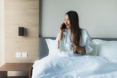 Young woman sitting on bed at home