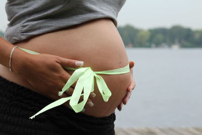 Midsection of pregnant woman with ribbon tied on stomach