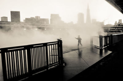 Man standing by railing in city against sky