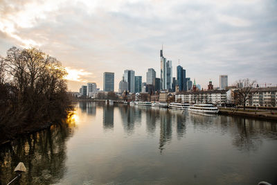 Scenic view of river by buildings against sky