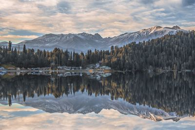 Mountains and trees reflecting on lake during winter