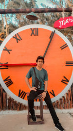 Portrait of young man standing against graffiti wall