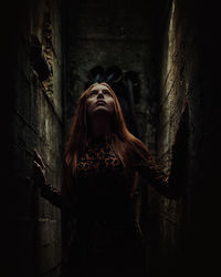 Woman standing amidst wall in alley