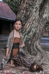 Young woman by tree looking away