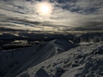 Scenic view of snow covered mountains against cloudy sky