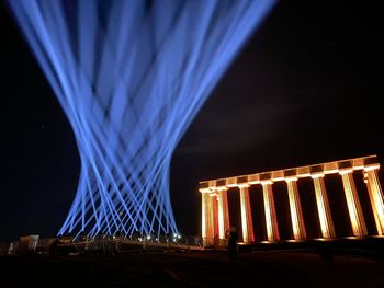 Illuminated bridge against blue sky at night