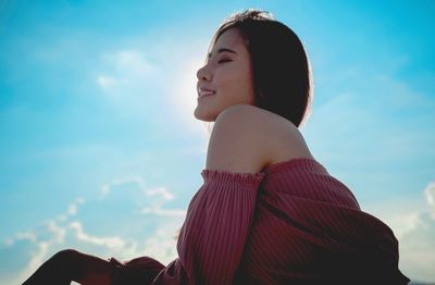 Smiling young woman against blue sky