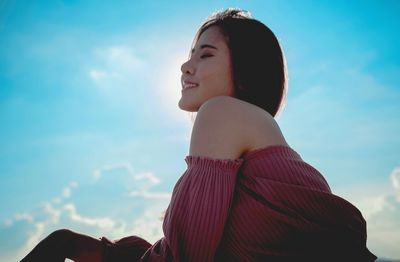 Low angle view of woman looking away against sky