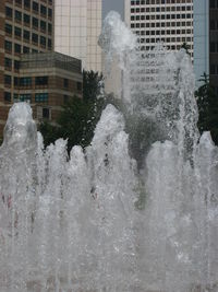 Water splashing on fountain against buildings in city