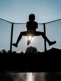 Silhouette man jumping in swimming pool against sky