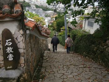 Rear view of people walking on street amidst trees