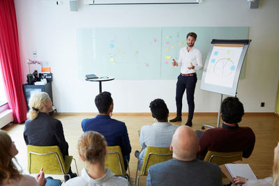 High angle view of businessman giving presentation to female and male colleagues in office seminar