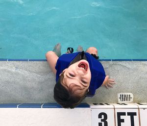 High angle portrait of boy sitting at poolside