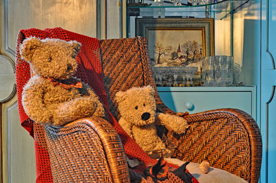 Teddy bears on wicker armchair at home