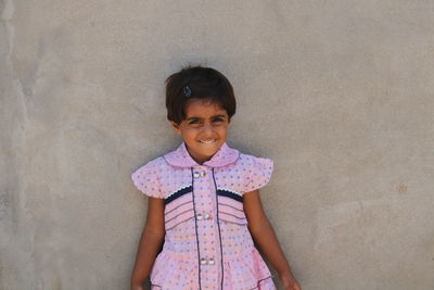 Portrait of smiling girl standing against wall