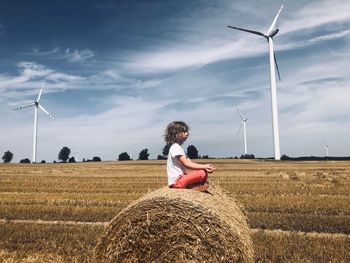 Wind turbines on field against sky