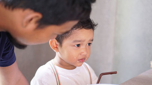 Close-up of man with messy toddler son at table