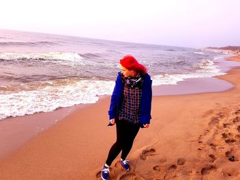 Rear view of woman walking on beach against clear sky