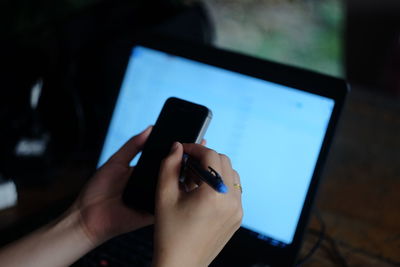 Cropped hands of woman using mobile phone in darkroom