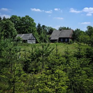 House and trees on landscape against sky