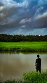 Rear view of man walking on field against sky