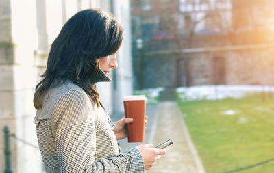 Young businesswoman using mobile phone while standing at lawn