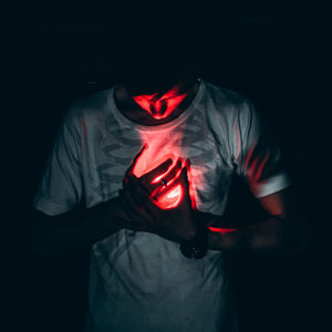 Midsection of man wearing mask against black background