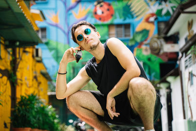 Young man wearing sunglasses sitting outdoors