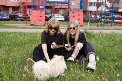 Two funny girls are eating ice cream and playing with a pomeranian dog. holidays