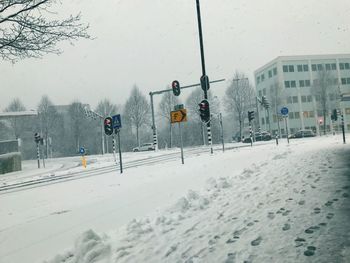 Snow covered road against buildings in winter