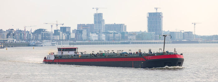 Boats in sea against buildings in city